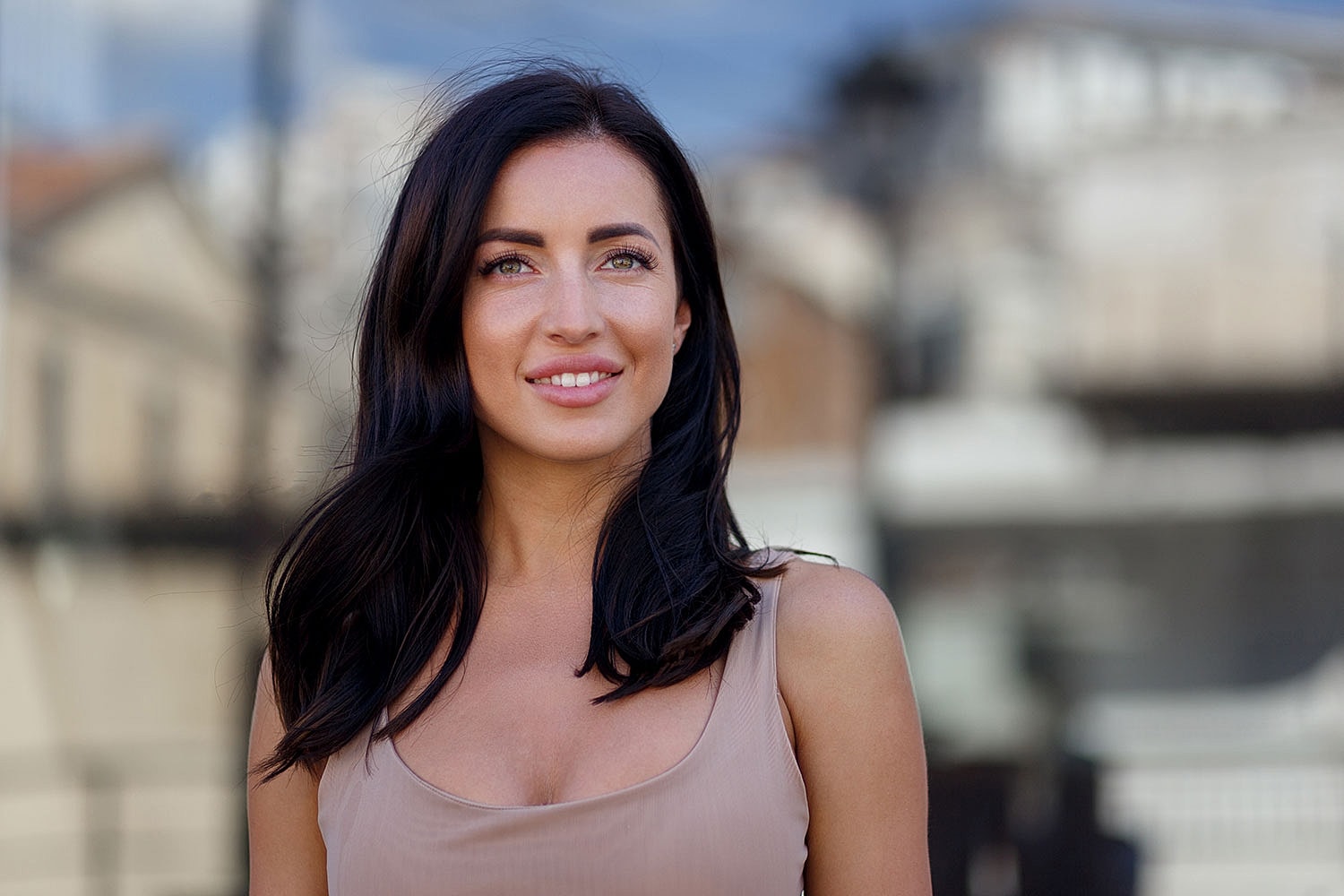 Smiling woman with long dark hair outdoors.