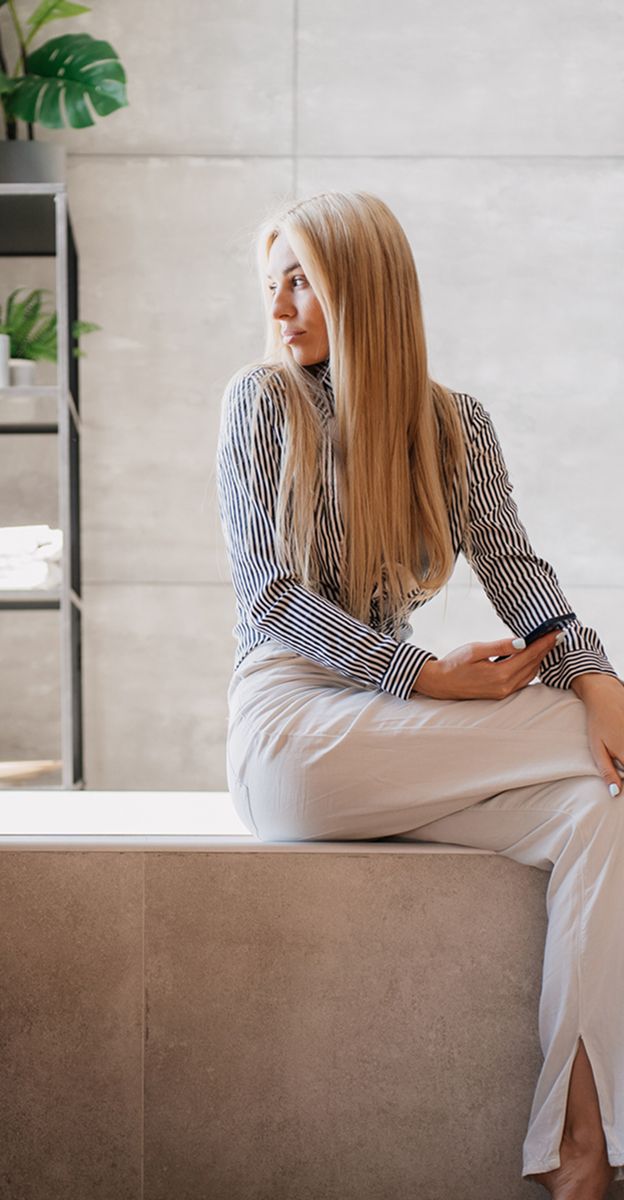 Woman sitting elegantly on a modern surface.