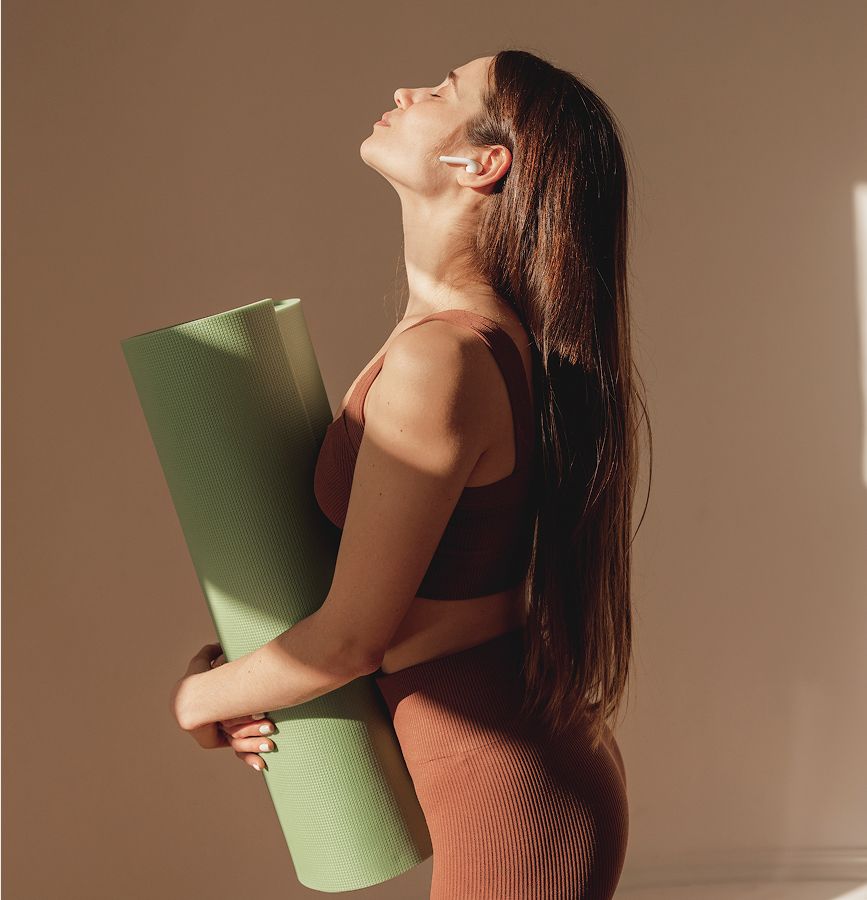 med spa patient model holding yoga mat in sunlit space.