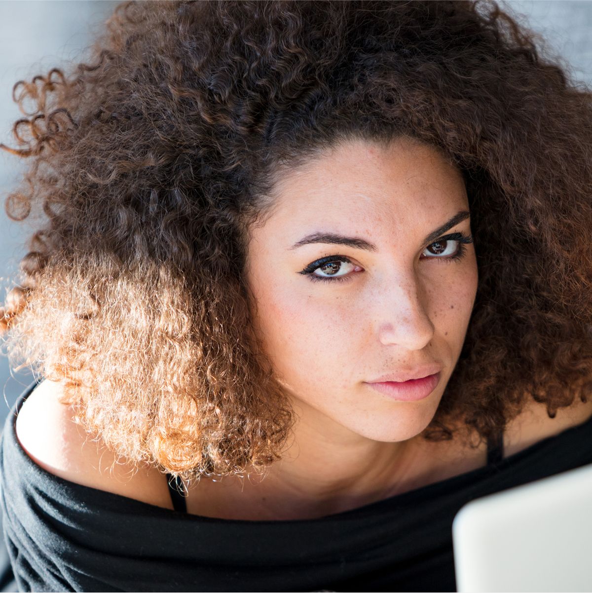 med spa patient model with curly hair looking thoughtfully at camera.