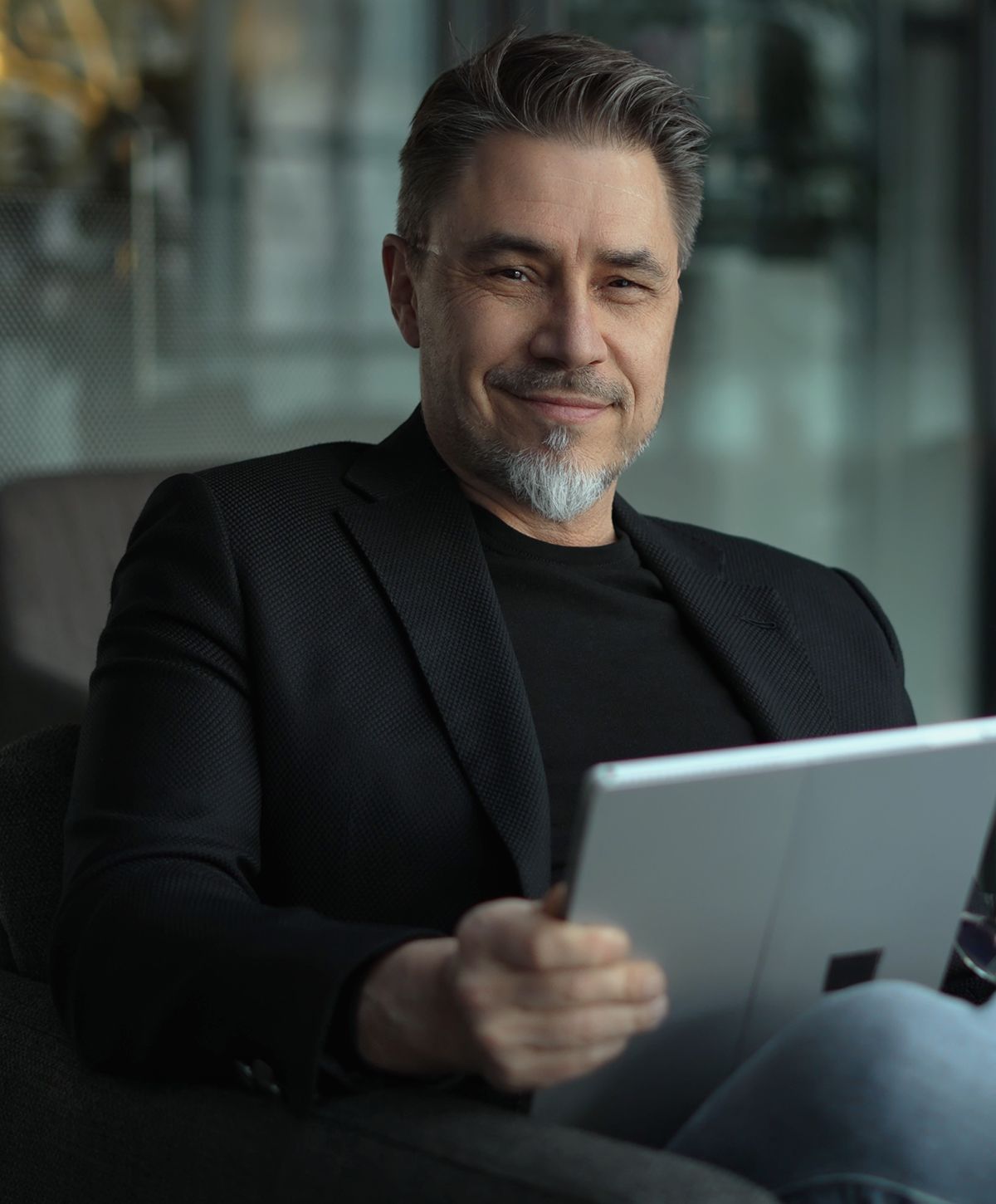 Smiling mens health patient model in a black blazer holding a tablet