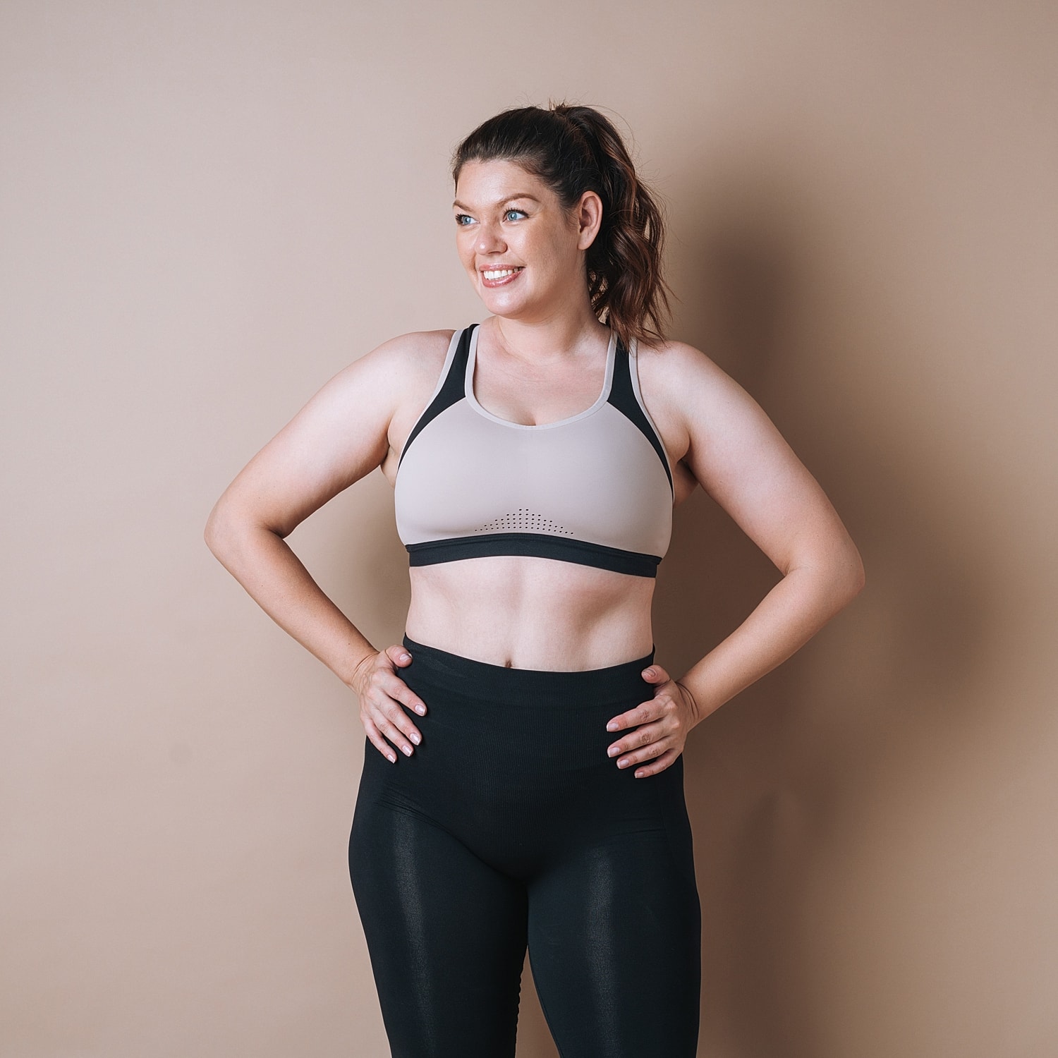 Smiling medical weight loss patient model in sports bra and leggings.