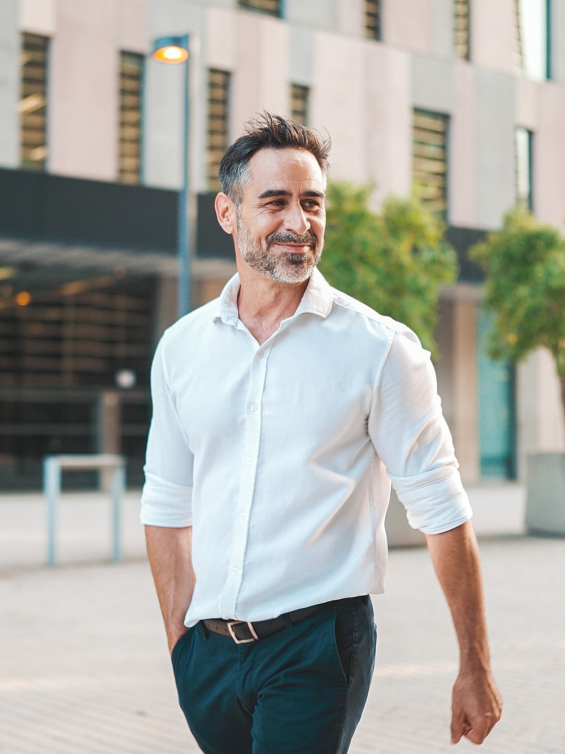 Smiling concierge medicine patient model walking in urban setting.