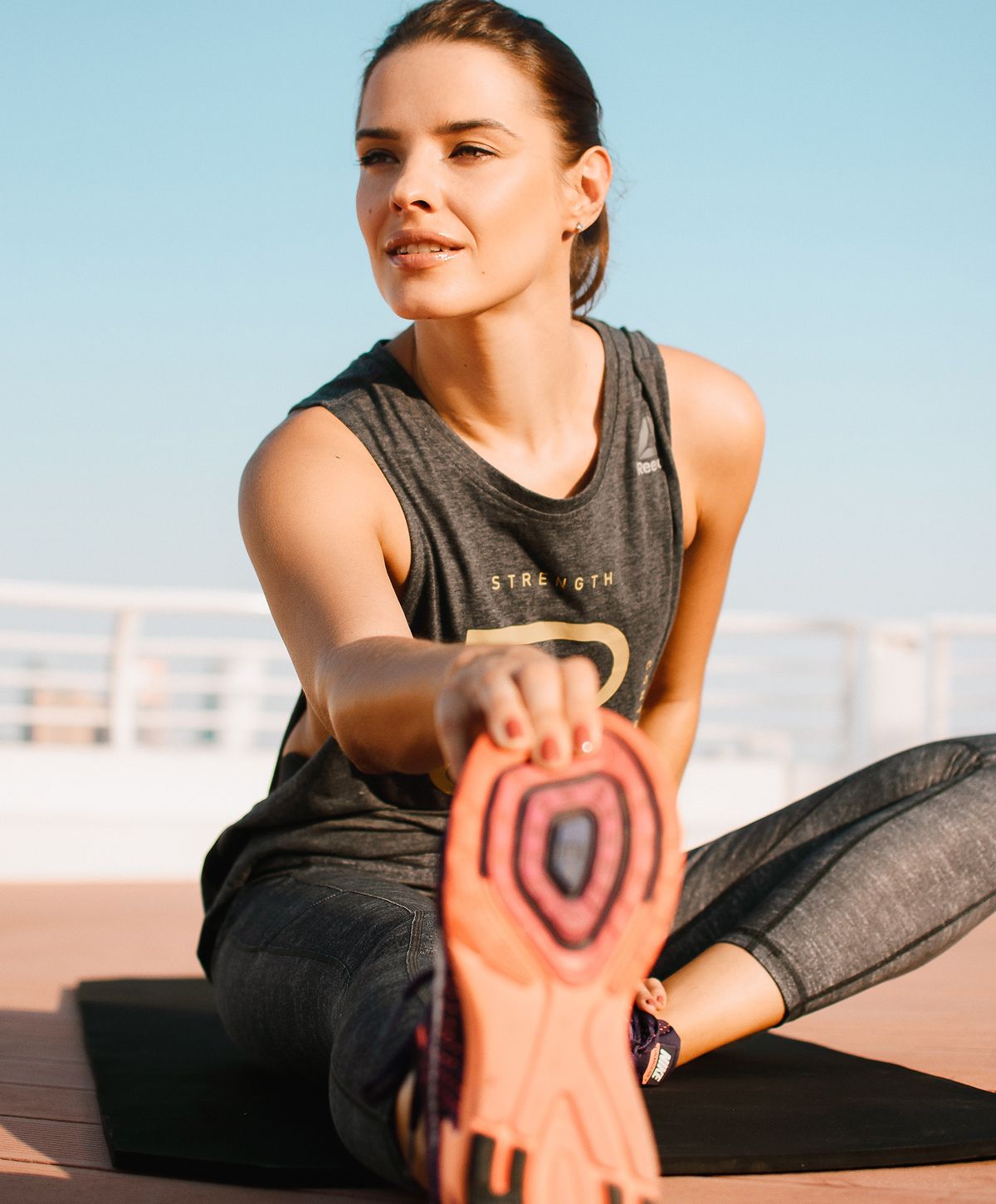 longevity medicine patient model stretching outdoors in athletic attire.