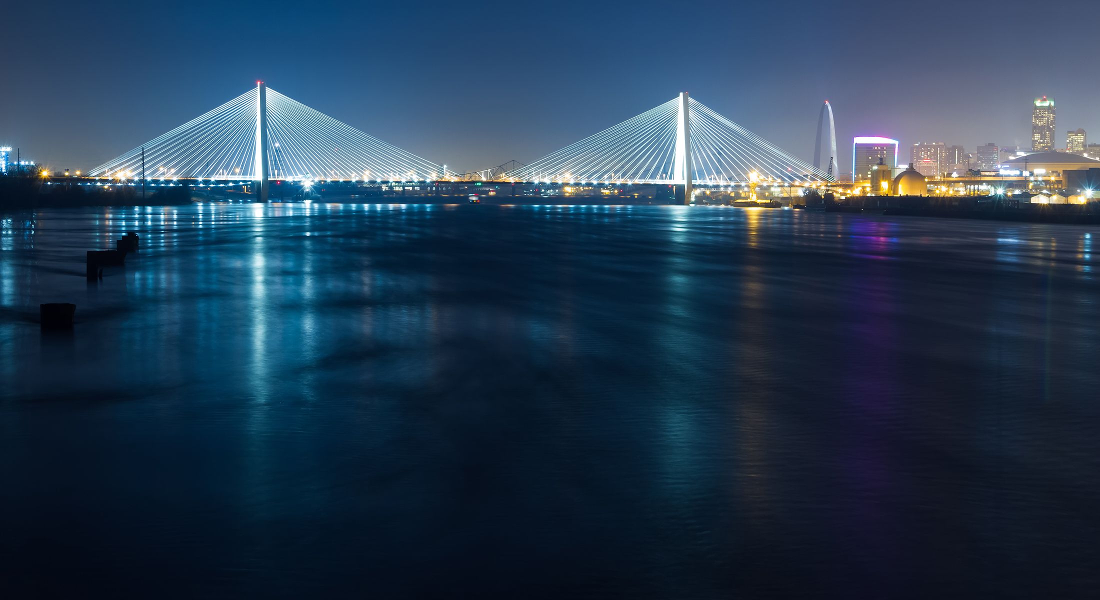 Illuminated bridge over a calm river at night.
